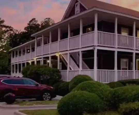 A close view of the inn's porch and white balustrade railing, with a car parked below at dusk