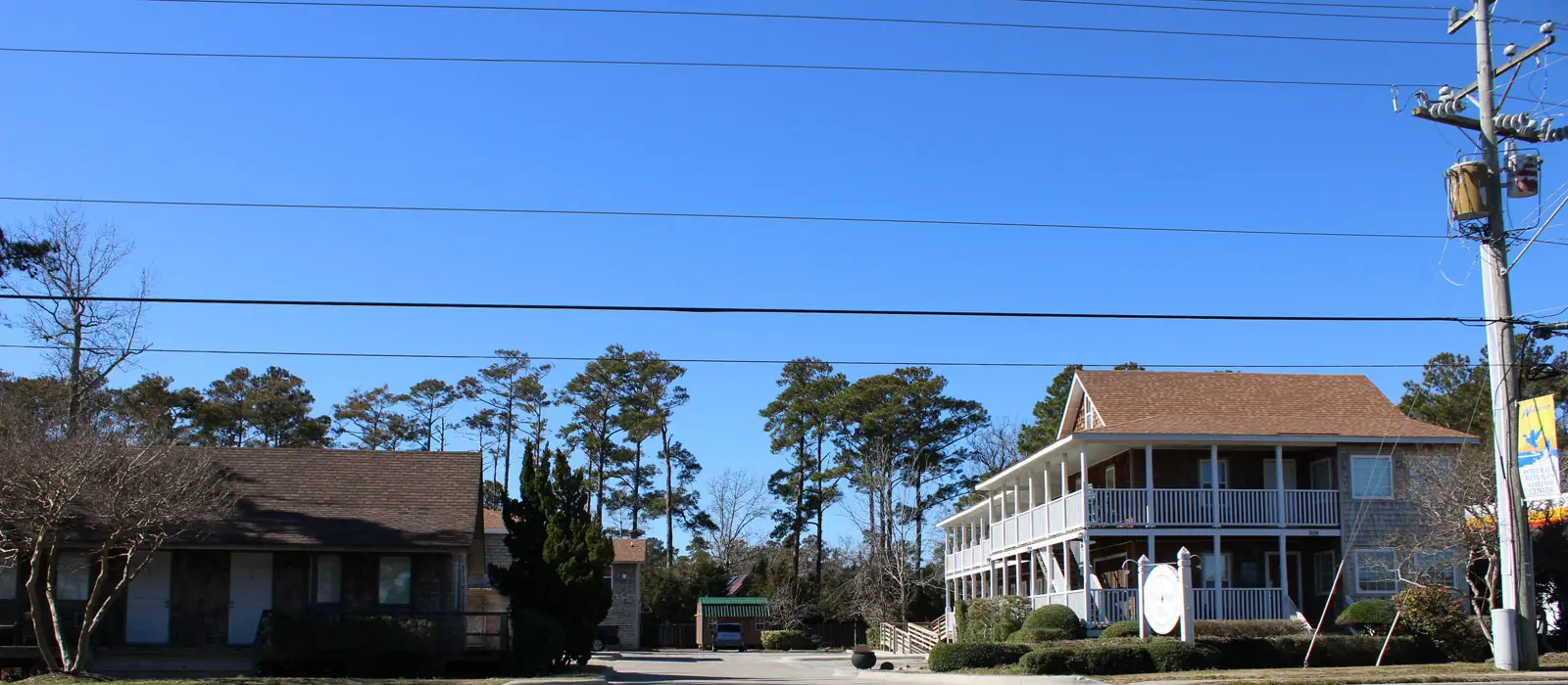 Several of the inn’s shingled buildings among tall pine trees, seen from the street