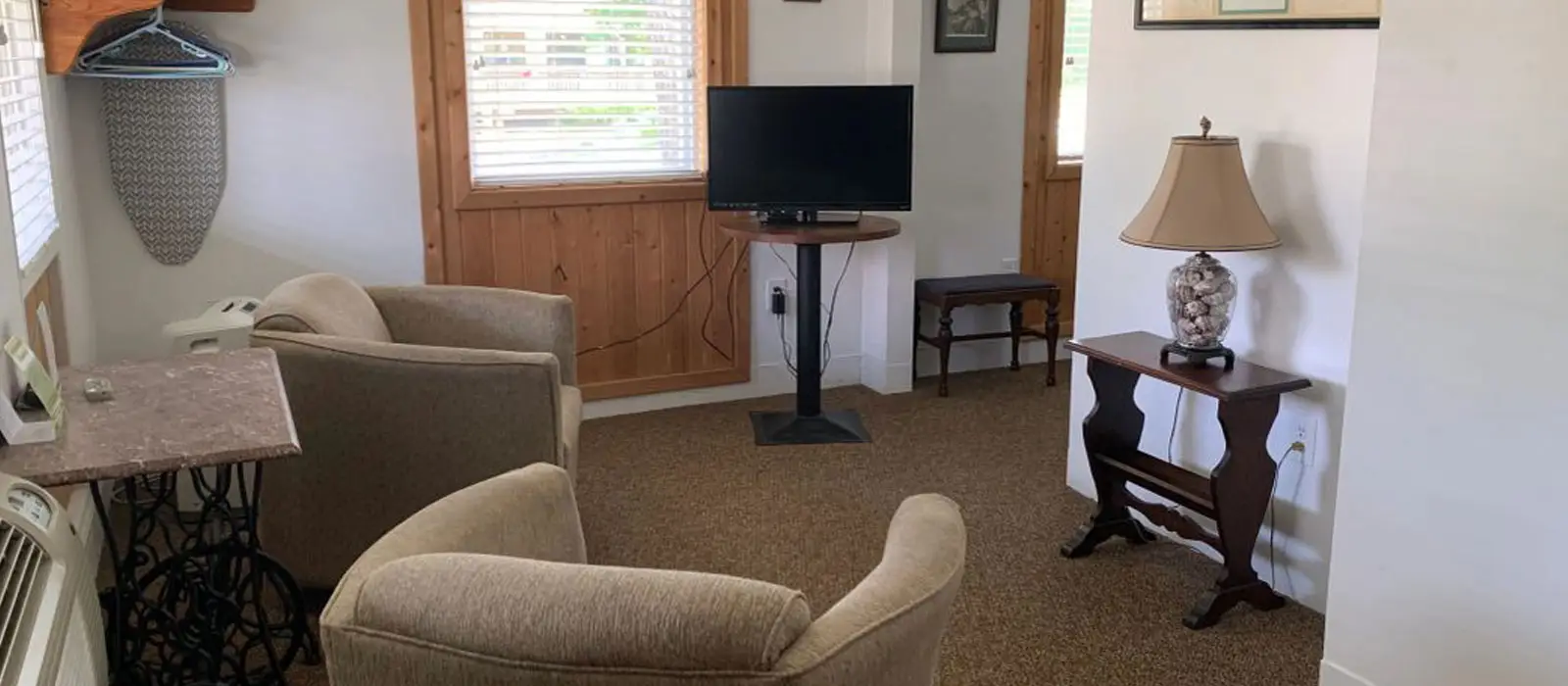 A common room with a red loveseat, a wooden dining table and chairs, and a wall-mounted television